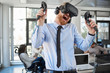 © nenadaksic - Employee in formal wear trying out VR technology in office. In background other employees working.