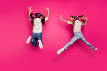 Sticker - Full length body size rear back behind view of two crazy cheerful cheery positive pre-teen girls having fun in air isolated over bright vivid shine pink background