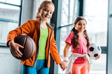 Wall Mural - Cute kids with balls holding hands in gym