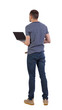 © ghoststone - Back view of a man who is standing with a laptop.