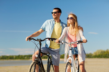 Sticker - people, leisure and lifestyle concept - happy young couple riding bicycles on beach