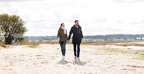 Poster - love, relationship and people concept - smiling couple walking along autumn beach and holding hands