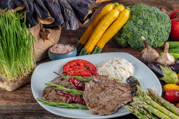 Medium rare beef tenderloin grilled, created background with vegetables on wooden background.