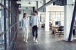 © opolja - On the way to business meeting. Full length of young modern people in smart casual wear having a discussion while walking through the office.