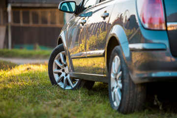 Wall Mural - New shiny gray car parked on green grass on blurred sunny summer rural background.