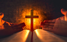 Cross With Bible And Light Of Candle Background On Wooden Table. Christian Praying Concept.
