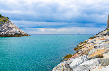 Strait between Portovenere town big stone promenade quay and Palmaria island rocks cliffs, Ligurian sea blue turquoise water, Riviera di Levante, National park Cinque Terre, La Spezia, Liguria, Italy