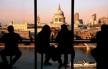 a couple tourists overlooking st paul's cathedral and millennium bridge at sunset.