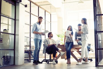 Sharing fresh ideas. Group of young business people in smart casual wear talking and smiling in the office hallway.