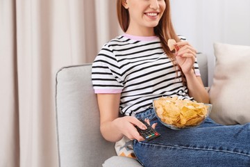 Canvas Print - Woman with bowl of chips on couch, closeup. Watching TV