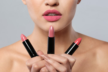 Poster - Young woman with lipsticks on gray background, closeup