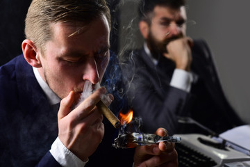 Waste of money. Man light up cigar from dollar banknote. Rich man smoking during business meeting. Businessmen have money to burn. Business partners writing financial report. Filthy with money