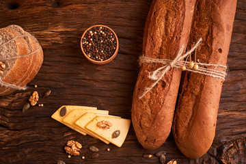 Peppercorns in a wooden bowl on table with stack of bread and two baguettes Homemade food