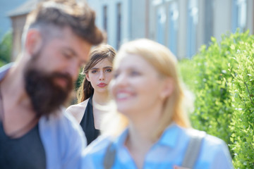 Wall Mural - Really jealous of him. Jealous woman look at couple in love on street. Romantic couple of man and woman dating. Bearded man cheating his girlfriend with another woman. Unhappy girl feeling jealous