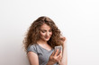© Halfpoint - Young beautiful happy woman in studio, using smartphone.