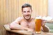 Męski relaks.   Przystojny mężczyzna zażywa kąpieli w bali z woda termalną pijąc piwo kuflowe.