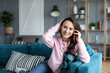 © BestForYou - Young smiling woman at home with phone.