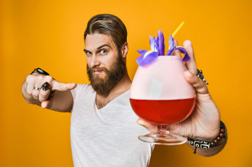 Young man holding a multicolored cocktail