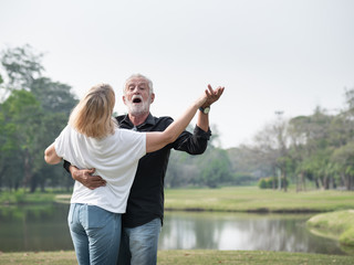 A happy senior couple smiling dancing in a park on a sunny day. relax in the forest spring summer time. free time, lifestyle retirement grandparents concept