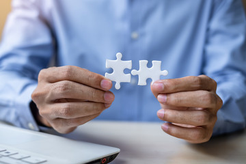 Businessman Hand connecting couple puzzle piece in office. Business solutions, mission, successful, goals and strategy concepts