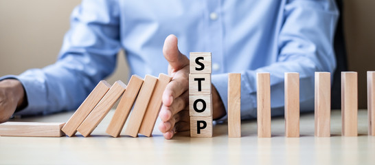 Businessman hand Stopping Falling wooden Blocks or Dominoes. Business, Risk Management, Solution, Insurance and strategy Concepts