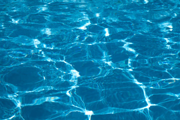 Wall Mural - Blue and bright ripple water surface in swimming pool with sun reflection.