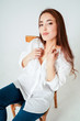 © Galina Zhigalova - Beauty fashion portrait of smiling sensual asian young woman with dark long hair in white shirt sitting on chair on white background