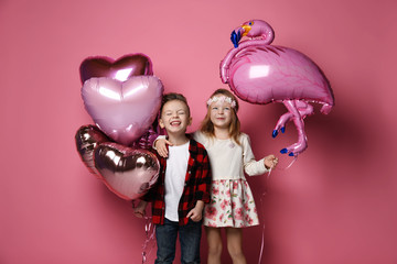 Little boy and girl kids with pastel color balloons for valentines day or birthday in kindergarten