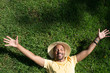 © KleverLevel - Happy African-American male model laying in the green grass with trendy straw hat and spread his hands.African man hipster treveler relaxing at park. Leisure and rest at summer day