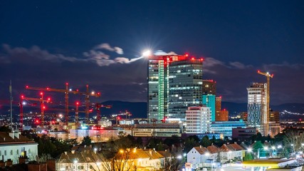 Moon touching the roof of an office building with a construction site on the left