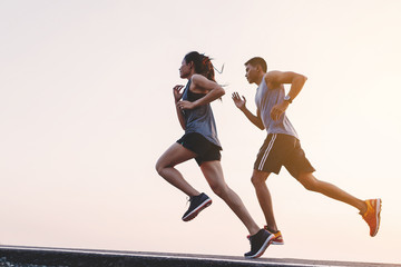 young couple runner running on running road in city park