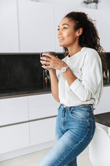 Wall Mural - Image of relaxed african american girl drinking tea, while standing in bright flat