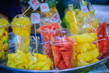 Fototapeta Boho - Fruit salad arranged in plastic cups for sale on street at Bangkok night market, Thailand.