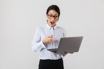 Wall Mural - Portrait of adult businesswoman wearing eyeglasses holding silver laptop in the office, isolated over white background