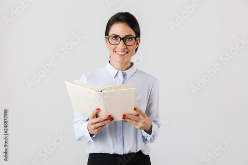 Fotografía Photo of smiling female worker wearing eyeglasses reading book in the office, is