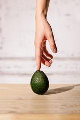 Fresh avocado pointing with hand and finger