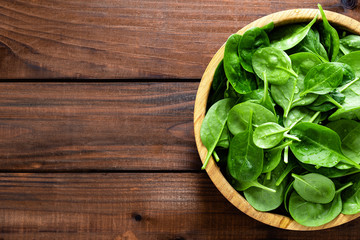 Canvas Print - Fresh spinach leaves on wooden background. Healthy vegan food. Top view.