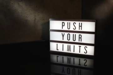 Push your limits motivational message on a light box in a cinematic moody background