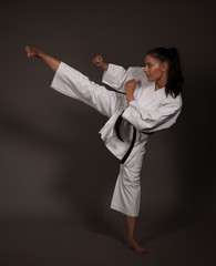 woman in white kimono kicks high in the air - a karate martial art girl