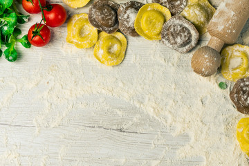 Wall Mural - Homemade fresh Italian ravioli pasta on white wood table  with flour, basil, tomatoes,background,top view.