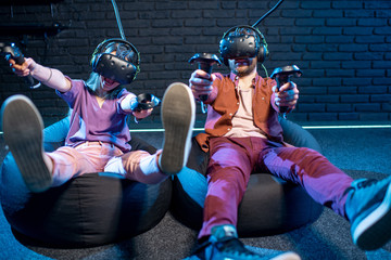 Man and woman shooting with gamepads while playing in virtual reality using VR headsets in the playing room