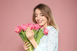 © New Africa - Portrait of beautiful smiling girl with spring tulips on pink background. International Women's Day