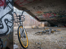 Old Yellow Scrap Bicycles Under Concrete Stairs With Graffiti And Homeless Sleeping Shelter