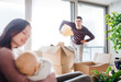 © Halfpoint - A portrait of young couple with a baby and cardboard boxes moving in a new home.