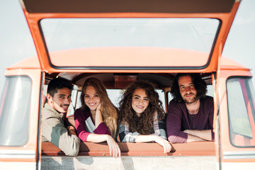 Wall Mural - A group of young friends on a roadtrip through countryside, looking out of window.