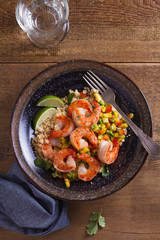 Wall Mural - Shrimps with mango avocado and red pepper salsa on cauliflower rice in bowl on wooden table. View from above, top studio shot