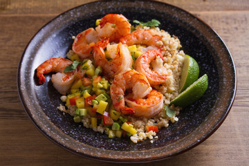 Wall Mural - Shrimps with mango avocado and red pepper salsa on cauliflower rice in bowl on wooden table