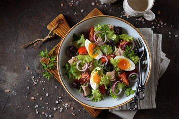 Healthy organic lettuce salad with canned tuna, cherry tomatoes, sun-dried olives, red onion, egg and parmesan. Top view. Copy space. 