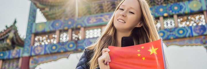 Wall Mural - Enjoying vacation in China. Young woman with national chinese flag on the background of the old Chinese street. Travel to China concept. Visa free transit 72 hours, 144 hours in China BANNER, LONG