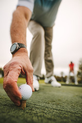 Golfer placing golf ball on tee at green